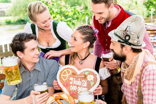 people with gingerbread heart in beer garden drinking beer in summer