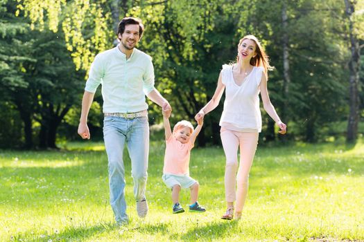 Family having walk together in summer holding hands and letting the little boy fly