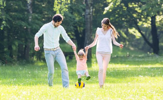 Family having walk together in summer holding hands and letting the little boy fly