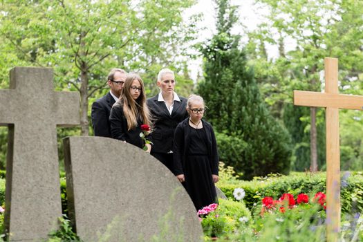 Family mourning at grave on graveyard or cemetery