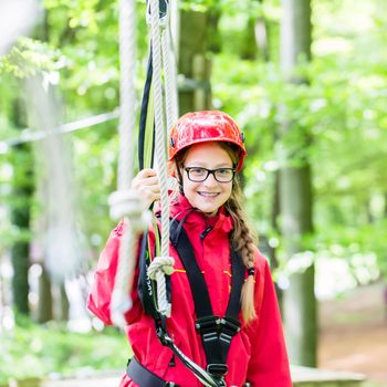 Girl roping up in high rope course exercising the necessary safety precautions