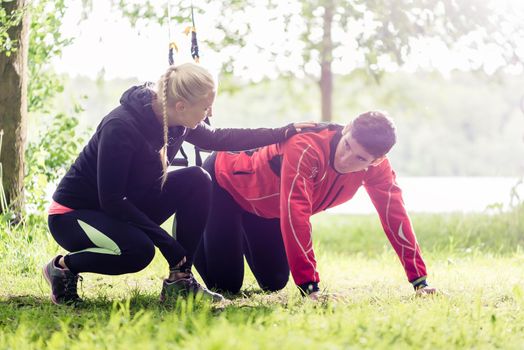 Sport couple outdoors with sling trainer