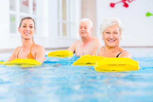 Senior and young people in water gymnastics with resistance device