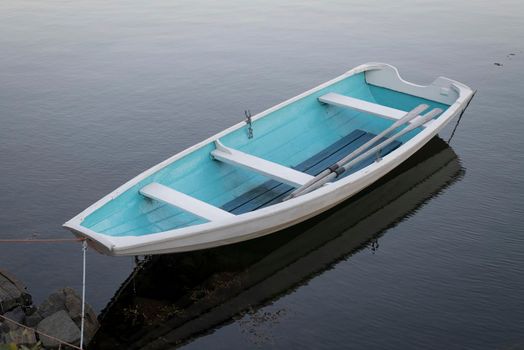 A boat on the lake near a dock, Sunset over the lake in the village. View from a wooden bridge with a boat aside