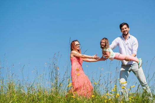 Family on meadow playing with their little daughter