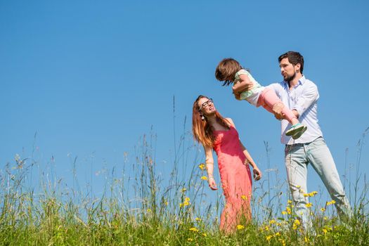 Family on meadow playing with their little daughter