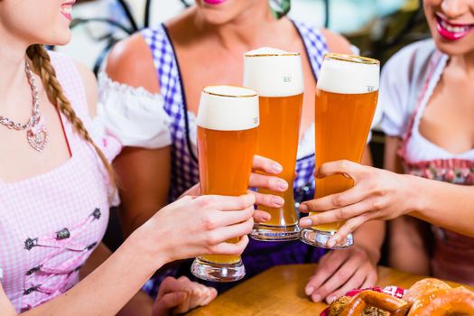 Close-up of people drinking beer in Bavaria toasting to each other wearing traditional Dirndl