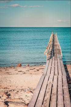 Wooden bridge on a tropical island, transparent sea and blue sky, advertising for tourism