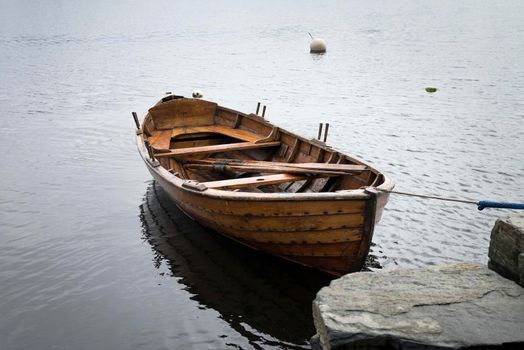 A boat on the lake near a dock, Sunset over the lake in the village. View from a wooden bridge with a boat aside