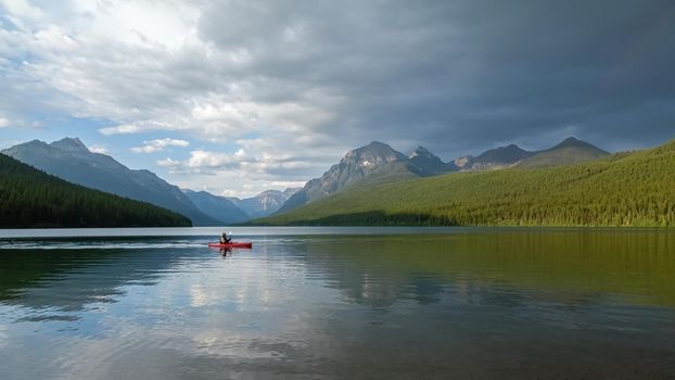 Man paddling on Bowman Lake in Glacier National Park, A terrific place to go camping, hiking, or fishing in Montana.