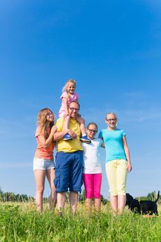 Family standing on meadow - father with children in grass