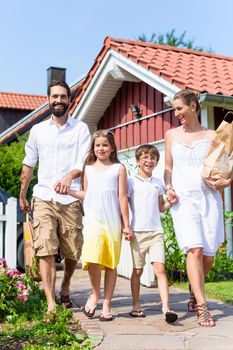 Family coming home from shopping groceries carrying bags