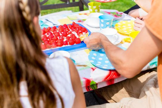 Family sitting in garden having coffee and cake