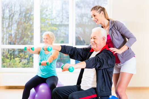 Physiotherapist coaching senior people exercising with dumbbells
