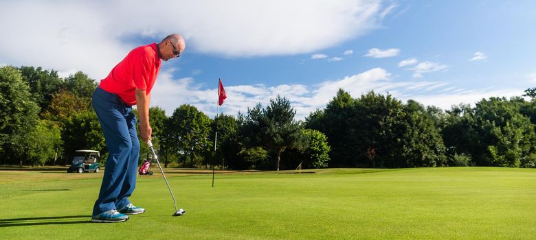 Senior golf playing man putting on green