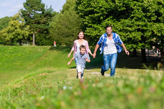 Family running fast in grass on meadow