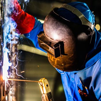 Welder working in an industrial setting manufacturing steel equipment