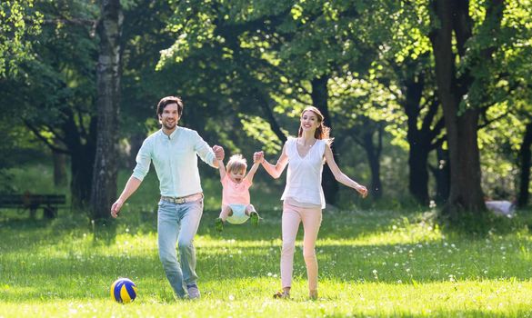 Family having walk together in summer holding hands and letting the little boy fly