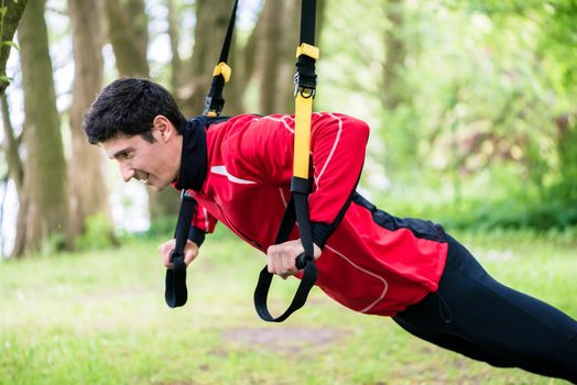 Man doing fitness sling training outdoors