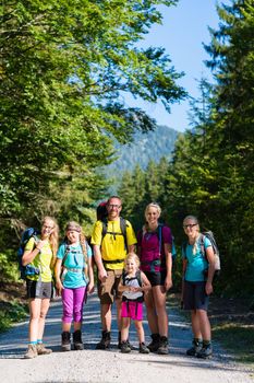 Family with four kids hiking in the mountains standing on path