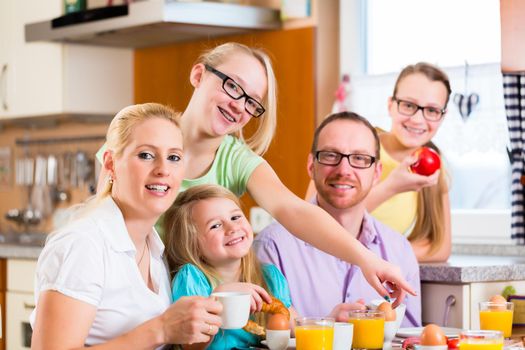 Family having joint breakfast in kitchen eating and drinking