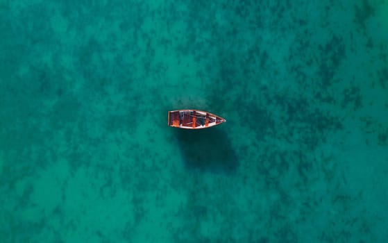 Aerial view of a wooden boat in the water, ship and boat in a beautiful turquoise ocean near an island, top view, aerial photo