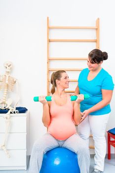 Pregnant woman working out with dumbbells in physical therapy