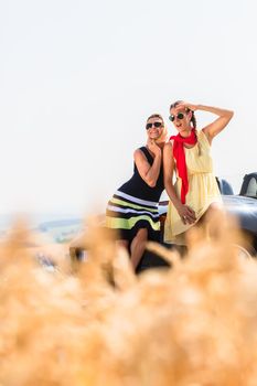 Women having joyride in convertible car having rest at grain field enjoying the landscape