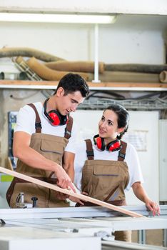 Carpenter and apprentice working together in wood workshop