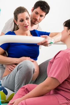 Woman laboring in delivery room with nurse and husband before birth