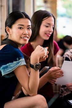 Young woman showing paperwork to her friends while sitting together in a coffee shop