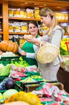 Woman buying pumpkin and vegetables in delicatessen