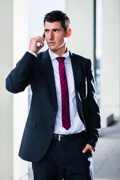 Business man with phone outdoors standing in front of building