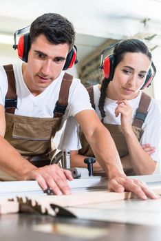 Carpenter and apprentice working together in their workshop