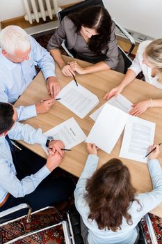 Lawyers having team meeting in law firm reading documents and negotiating agreements