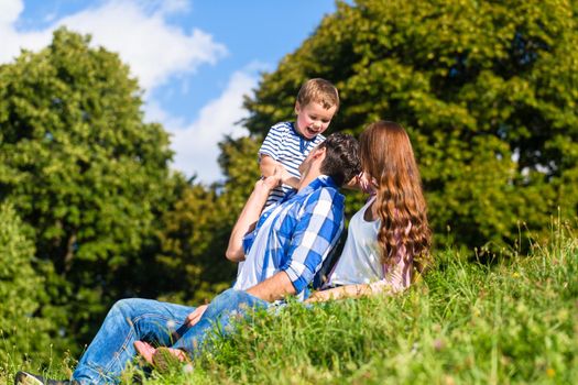 Family having fun sitting in the green grass