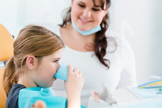 Child in Dentist surgery flushing teeth with water