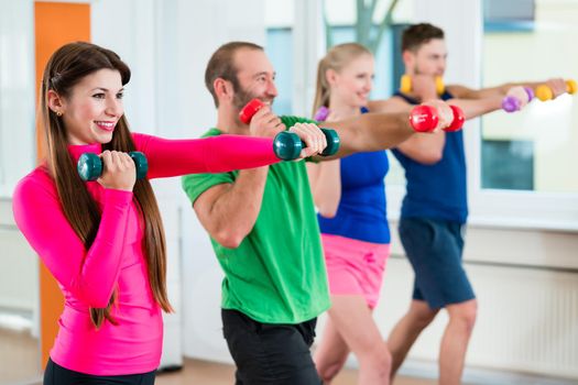 Men and woman doing workout with small weights in fitness studio gym