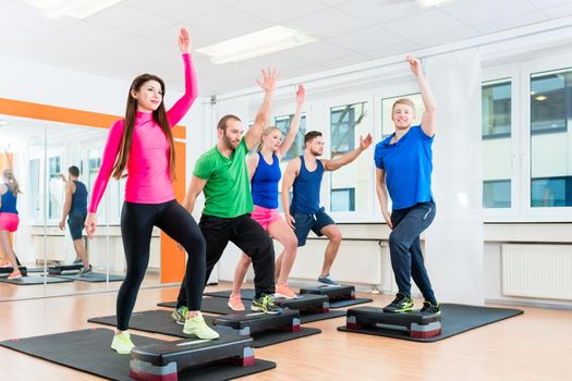 Workout group in fitness hall doing gymnastics with stepper