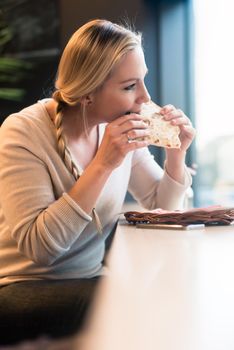 Woman eating a sandwich in train taking a bite