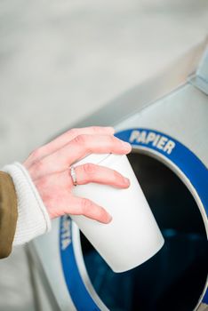 Woman using waste separation container throwing away coffee cup made of Styrofoam