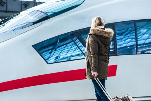 Woman waiting for her train with luggage in station ready to travel