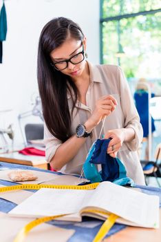 Asian fashion designer woman sewing in her workshop for the new collection