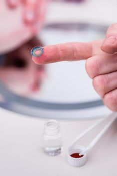 Saleswoman in optician shop showing contact lens at camera