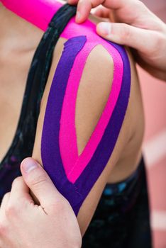 Woman taping with therapeutic tape on cinder track of sports stadium