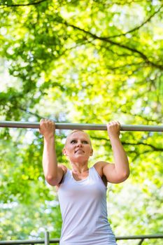 Woman exercising at high bar for better outdoor fitness