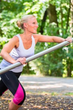 Young woman stretching before sport on fitness trail in summer