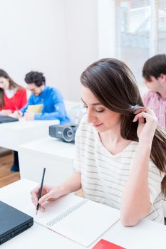 Student woman writing test in seminar room of university or having exam