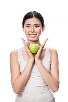 Thoughtful young Asian woman holding a green apple against white background