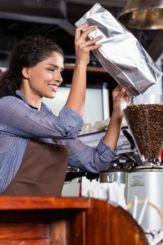 Barista in Indian cafe filling coffee grinder with coffee beans